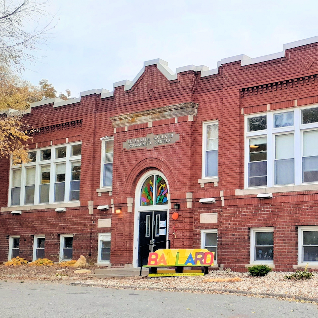multi story red brick building with ballard center sign in front
