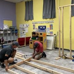 two men in a classroom working to build the frame of a closet