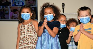 group of young children wearing masks and clipping their hands