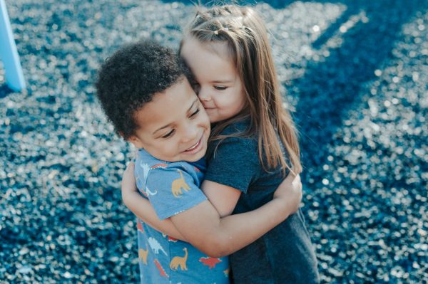 a young boy and girl hugging each other on a playground